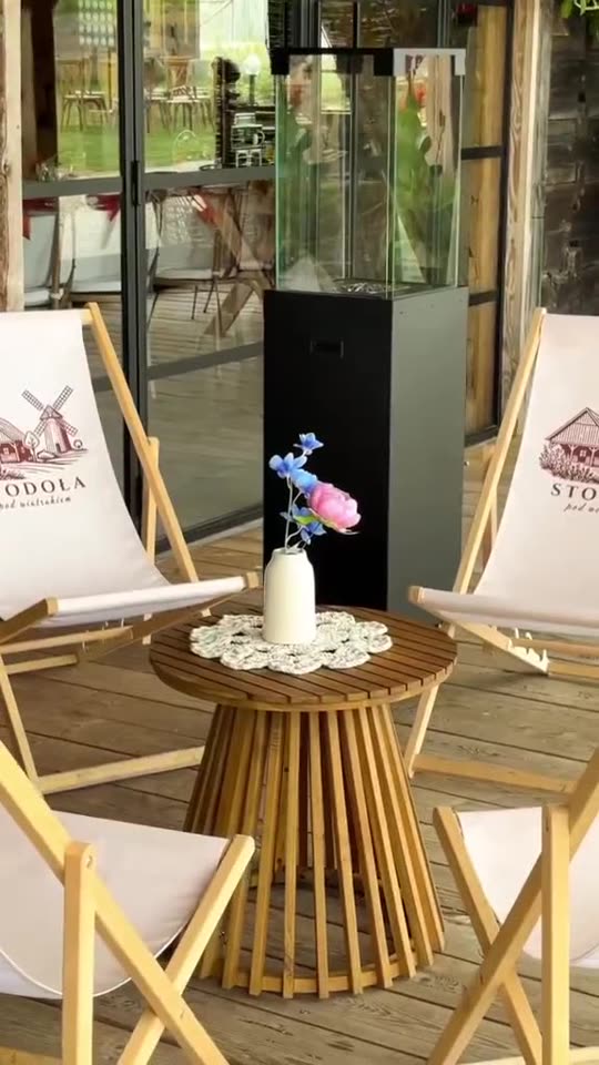 Taras z leżakami z logo stodoły i stolikiem z kwiatami